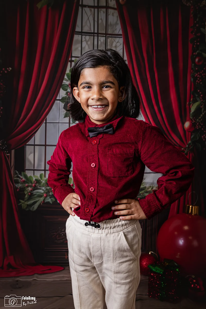 Lachend kind in een rood overhemd met strik voor rode kerstgordijnen